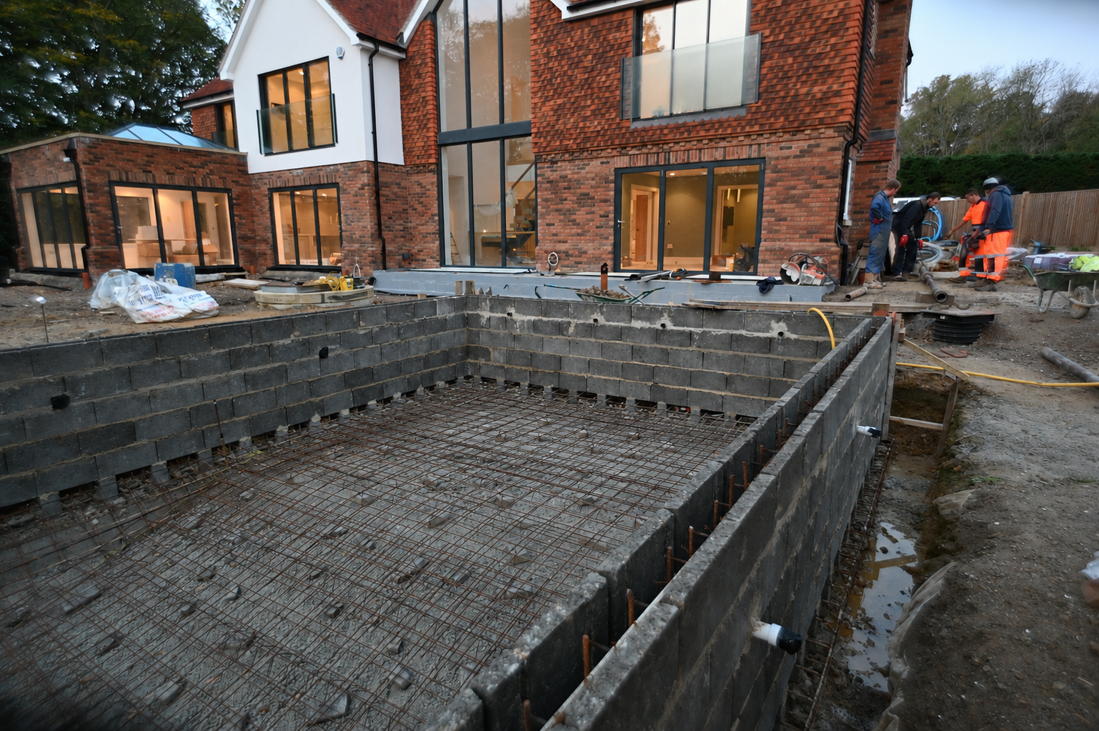 Mermaid pool under construction, showing reinforcing mesh, blockwork and the team working beside the house